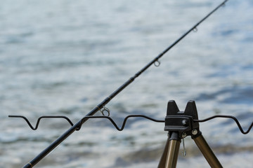 Obraz premium The fishing rod on the tripod in front of a river.