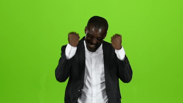 African american in the strict black suit is happy with his victory. Green Screen. Slow motion