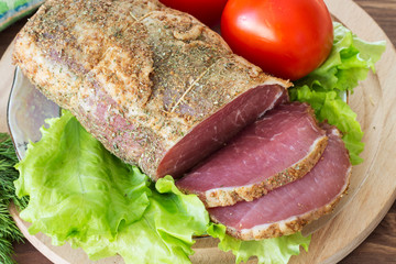 Slices of bacon and fresh lettuce and tomatoes on a wooden board. Selective focus.
