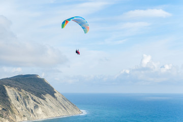 Flying tandem paragliders over the sea and near the mountains, beautiful landscape view