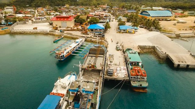 Cargo and passenger port with barges and cargo ships on tropical island. Aerial view:passenger ferry terminal Dapa city .Ferries for transport vehicles and passengers in the port. Philippines, Siargao