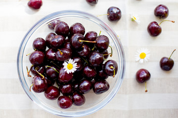 Sweet tempting cherries in a glass bowl and on the table