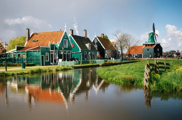 Naklejka na ściany i meble Authentic Zaandam mills and traditional vibrant houses on the water canal in Zaanstad village, Zaan river, Netherlands