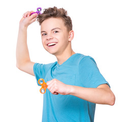 Young teen boy holding popular fidget spinner toy - close up portrait. Happy smiling child playing...