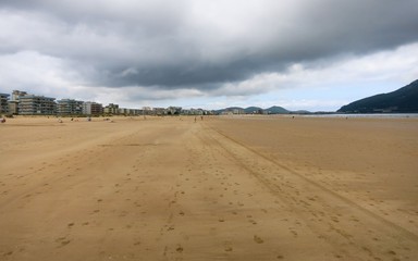 Fototapeta na wymiar Sandy beach with footprints and houses in the background. Spain.