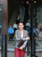 Beautiful young business woman open door and walking outside.