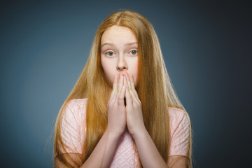 Little girl with astonished expression while standing against grey background