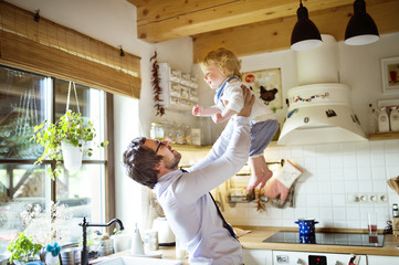 Businessman coming home, holding his son high in the air.