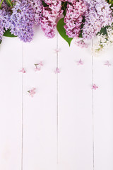 Spring white, violet and purple lilac flowers on white wooden background. Top view with copyspace, flat lay.