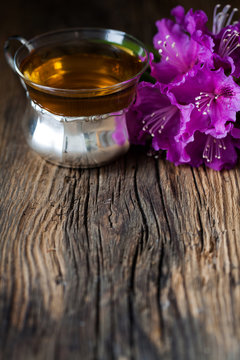 tea and purple rhododendron on wood - wooden table
