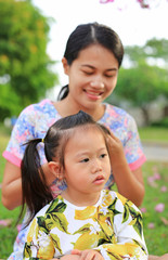 Mother tying her daughter's hair back in the garden.