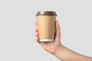 Mockup of male hand holding a Coffee paper cup isolated on light grey background. 