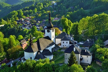 Spring in Slovakia. Old mining village. Historic church in Spania dolina. Springtime colored trees at sunset. - obrazy, fototapety, plakaty