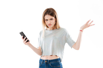 Young confused girl holding mobile phone and shrugging shoulders