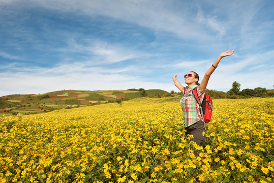 Traveler with backpack enjoying of colored fields view with raised hands