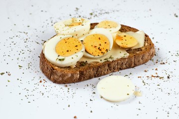 One sliced bread with cut and whole boiled egg. On white.