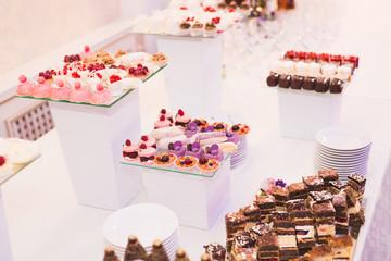 Delicious and tasty dessert table with cupcakes shots at reception closeup