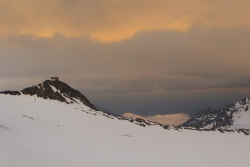 Alpine hut at stormy sunset