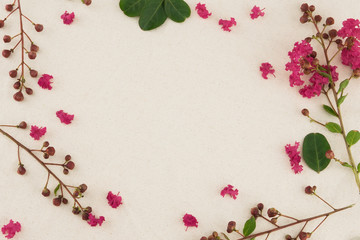 Pink crape myrtle petals, leaves and budding flowers on muslin fabric with copy space