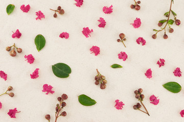 Pink crape myrtle petals, leaves and budding flowers on muslin fabric 