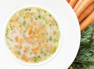 Vegetable carrot soup and ingredients on wooden table. Top view.