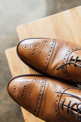 close up of brown leather oxford shoes on wooden stool
