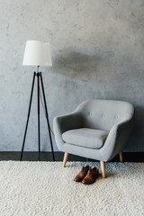 leather oxford shoes on carpet near textile armchair and lamp at empty room