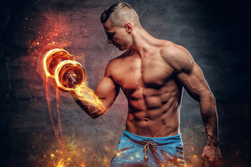 Athletic young male holds dumbbell.