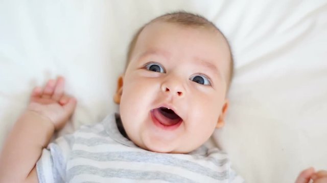child is happy and laughing lying on bed at home