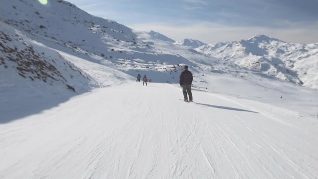 Skiers skiing on a ski slope piste in alpine winter resort with blue sky