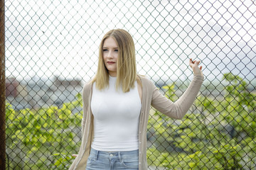 Closeup of pretty young woman standing near chain link fence