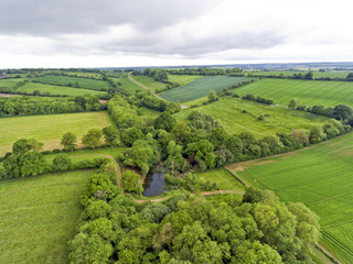 Aerial view  landscape of green fields, meadows, small lake hidden in the trees, in an english countryside, on an overcast summer day . - 158860627