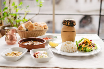 Traditional turkish pottery kebab on the table with rice and salad