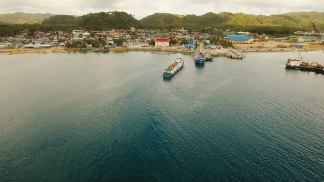 Cargo and passenger port with barges and cargo ships on tropical island. Aerial view:passenger ferry terminal Dapa city .Ferries for transport vehicles and passengers in the port. Philippines, Siargao