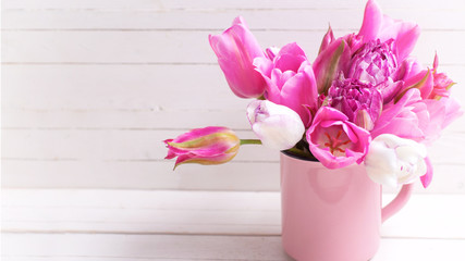 Variety of bright pink  spring tulips flowers in pink  cup on white  wooden background.