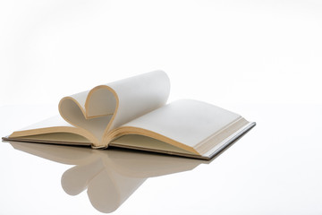 Open book with blank pages folded into heart shape.