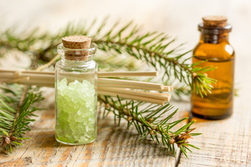 spa with organic spruce oil and sea salt in glass bottles on wooden table background
