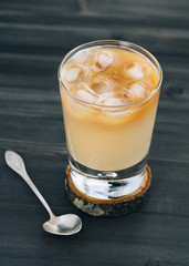 Close-up of a refreshing iced coffee with milk in glass on a wooden black table.