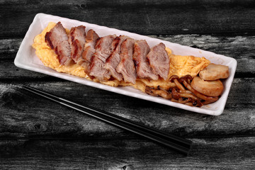 Omelet topped pork steak and grilled mixed mushroom.