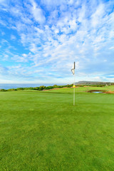 Fototapeta premium Golf pin on a beautiful seaside course with blue sky.