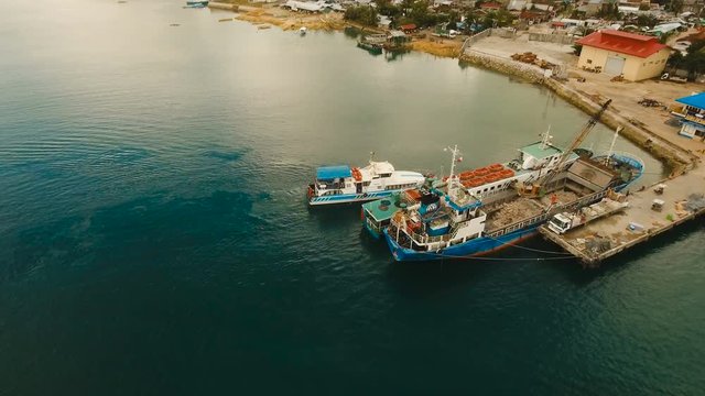 Cargo and passenger port with barges and cargo ships on tropical island. Aerial view:passenger ferry terminal Dapa city .Ferries for transport vehicles and passengers in the port. Philippines, Siargao