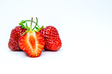 Two whole berries of strawberries and a cut berry in the foreground.