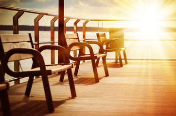Amazing beach landscape with chairs for relaxation on wooden terrace. Bright sun rays. Travel background in vintage style.
