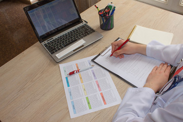 Doctor sits in a medical office in the clinic and writes medical history. Medicine doctor's working table