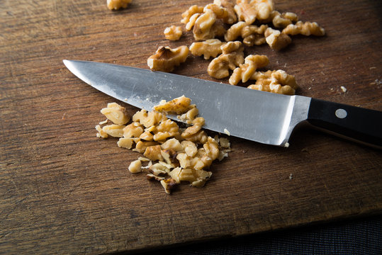 Sharp Chef Knife Chopping Walnuts On Rustic Vintage Chopping Board