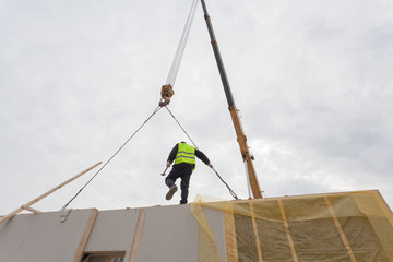 Roofer builder workers with crane installing structural Insulated Panels SIP. Building new frame energy-efficient house