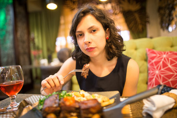 Girl eating fried meat in a restaurant