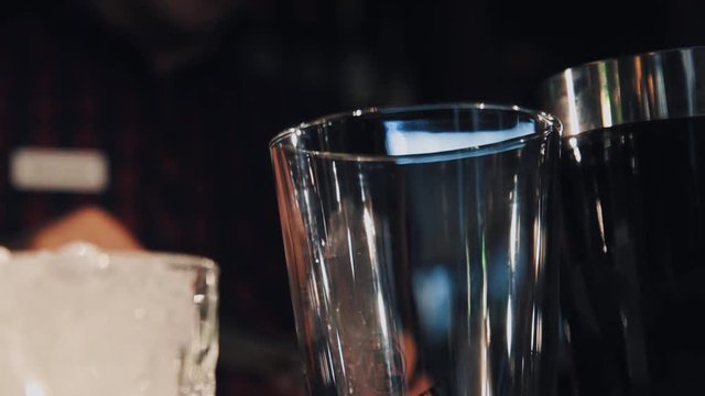 Unrecognisable bartender hand puts raspberry using metal tweezers into glass making cocktail close up