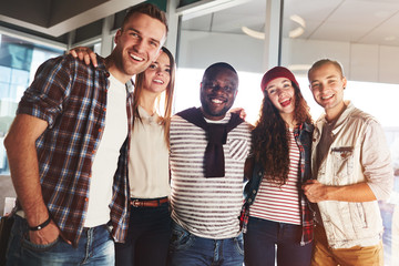 Obraz premium Low angle view of joyful young friends looking at camera with toothy smiles while having fun together in cozy cafe