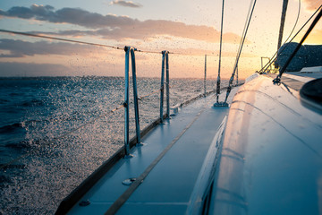 Sailing yacht at sunset, the waves and splashes